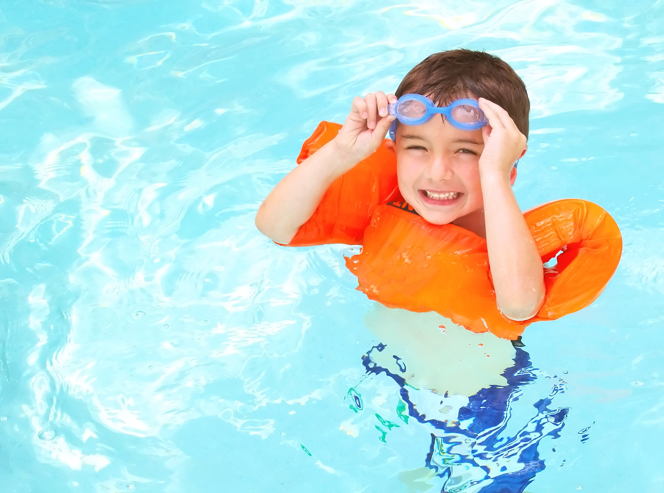 Young boy in floaties in a pool.