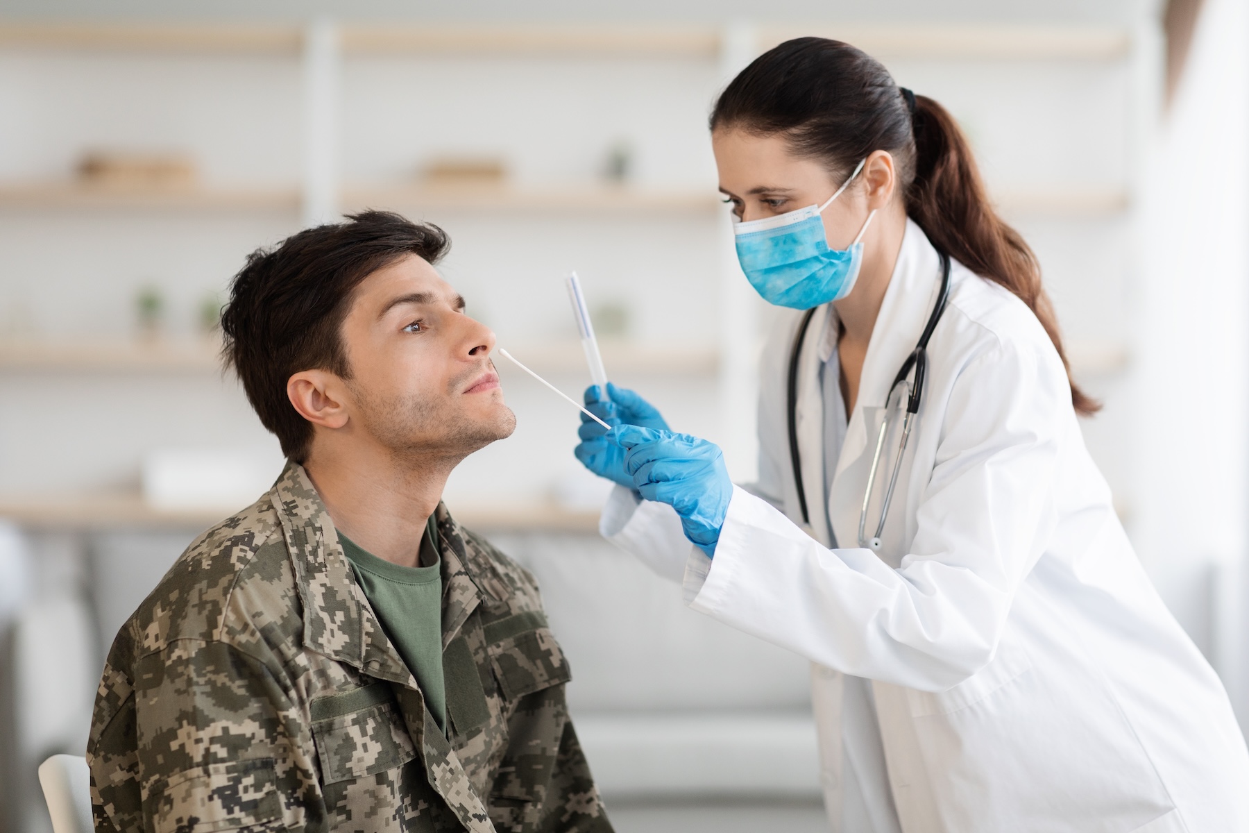 Urgent care worker taking sample for PCR test from soldier